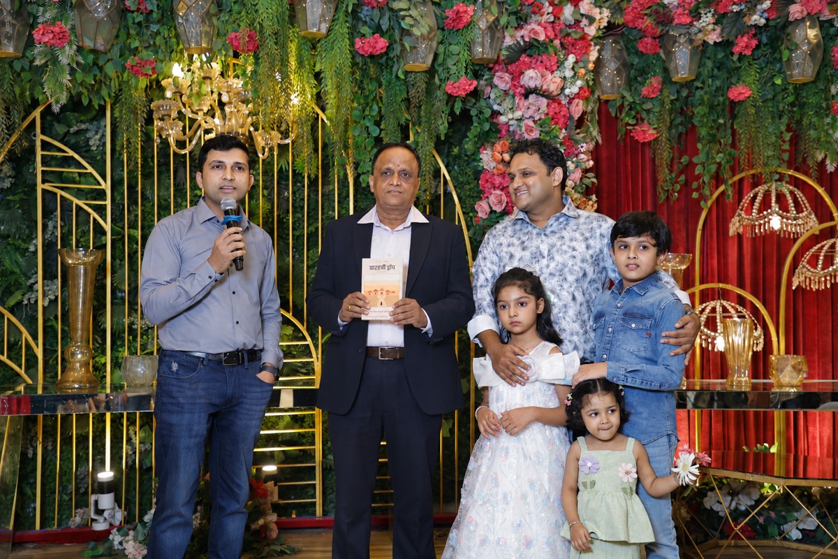 Sunil Kumar Jain holding 12th Drop on stage at his retirement function, surrounded by his sons and grandchildren